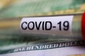 Corona virus covid-19 uncertain consequential costs concept symbol: macro closeup of isolated blood sample vial on 100 us dollar Royalty Free Stock Photo