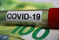 Corona virus uncertain consequential costs concept symbol: macro closeup of isolated blood sample vial on 100 euro paper bank note