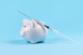 Corona virus vaccine expenses or cash infusion concept with white piggy bank and syringe on blue background