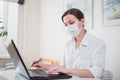 Coronavirus. Business woman working from home wearing protective mask.