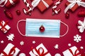 Coronavirus Christmas concept. Face mask in frame made of Christmas gift boxes and decorations on red background Royalty Free Stock Photo