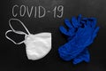 Coronavirus concept. blue medical gloves and a white mask on a black background with chalk inscription coronavirus. Epidemic of