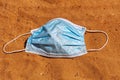 Coronavirus, concept. Blue surgical mask abandoned or forgotten by the owner on the beach, in the sand Royalty Free Stock Photo