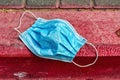 Coronavirus, concept. Blue surgical mask abandoned or forgotten by the owner on the curb separating the sidewalk Royalty Free Stock Photo