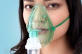 Coronavirus Concept. Chinese woman in oxygen mask standing isolated on grey breathing pensive close-up