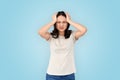 Coronavirus Concept. Chinese woman standing isolated on grey holdinghead having headache wincing from pain Royalty Free Stock Photo