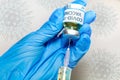 Coronavirus conceptual image of doctor hand in surgical glove holding a vaccine bottle with injection syringe in close up view Royalty Free Stock Photo