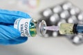 Coronavirus conceptual image of doctor hand in surgical glove holding a vaccine bottle with injection syringe in close up view Royalty Free Stock Photo