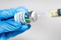 Coronavirus conceptual image of doctor hand in surgical glove holding a vaccine bottle with injection syringe in close up view Royalty Free Stock Photo