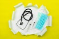 Coronavirus or Covid-19 Medical mask with Stethoscope and syringe in Yellow ripped open paper background