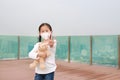 Covid-19 and pollution protection concept. Asian little child girl hugging teddy bear doll with wearing mask and show Royalty Free Stock Photo