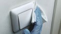 Cleaning the white switch in gloves with a white cloth, pandemic coronavirus