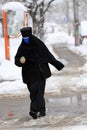 Coronavirus or Covid-19 prevention. A nun with a face mask for virus protection walks down the street in the snow