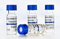 Coronavirus Covid 19 vaccine concept - small glass vials with blue caps on white table, closeup detail own sticker design with