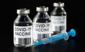 Coronavirus Covid-19 vaccine concept -  three glass vials on black table, blue syringe near closeup detail own design - dummy bar Royalty Free Stock Photo
