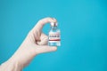 Coronavirus COVID-19 vaccine and immunization concept. hand in white glove holding vaccine bottle for injection isolated on blue Royalty Free Stock Photo