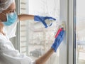 Coronavirus disinfection. People in making disinfection on windows. Doctor in rubber gloves disinfects windows handle