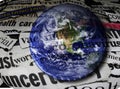 Coronavirus and economic related newspaper headlines superimposed over an image of the earth