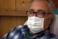 Coronavirus. Elderly gray-haired sick man with corona virus wearing mask protection recovering from the illness in home.