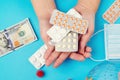 Coronavirus epidemic. Woman hands holding protective pills against the virus. Background with money, pills, coronavirus details.