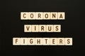 CORONAVIRUS FIGHTERS - words from wooden blocks with letters. Top view on gray background.