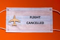 Coronavirus flight cancellations concept. Face mask and airplane toy on orange background. Words `flight cancelled