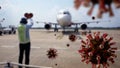 Coronavirus floating on air while airport worker signaling to plane pilot