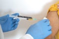 Coronavirus. The hands of a doctor injecting the covid-19 coronavirus vaccine to a woman in a yellow shirt Royalty Free Stock Photo