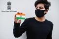 Indian man wear all black and face mask, hold India flag in hand isolated on white background with Mizoram state emblem .