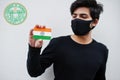 Indian man wear all black and face mask, hold India flag in hand isolated on white background with Telangana state emblem .