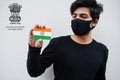 Indian man wear all black and face mask, hold India flag in hand isolated on white background with Dadra Nagar Haveli Daman and