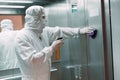 Coronavirus infection. Paramedic in protective mask and costume disinfecting an elevator with sprayer,