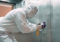 Coronavirus infection. Paramedic in protective mask and costume disinfecting an elevator with sprayer,