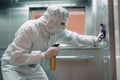 Coronavirus infection. Paramedic in protective mask and costume disinfecting an elevator with sprayer, Royalty Free Stock Photo