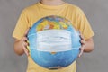 Coronavirus.Kid holding earth globe with medical face mask.Covid 19 concept Royalty Free Stock Photo