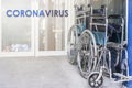 Coronavirus lettering on a white background of a hospital emergency room, and a folded wheelchair. hospitalization of patients and Royalty Free Stock Photo