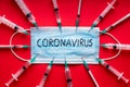 Coronavirus - 2019-nCoV, WUHAN virus concept. Surgical mask protective mask on red background with many syringes pointing at