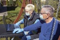 COVID 19 An elderly couple a man and a woman in medical masks in front of a laptop in a garden in a nursing home