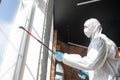 Coronavirus Pandemic. A disinfector in a protective suit and mask sprays disinfectants in the house or office