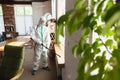 Coronavirus Pandemic. A disinfector in a protective suit and mask sprays disinfectants in the house or office