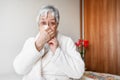 Coronavirus pandemic. Healthcare, flu, hygiene and people concept. Sick senior woman with paper wipe blowing his nose at Royalty Free Stock Photo