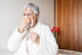 Coronavirus pandemic. Healthcare, flu, hygiene and people concept. Sick senior woman with paper wipe blowing his nose at Royalty Free Stock Photo