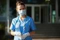 Modern physician woman in scrubs outdoors near hospital