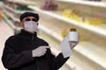 Coronavirus panic concept. Man with surgical mask, hood, glasses and medical gloves shows a roll of toilet paper with an abstract