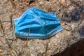 Coronavirus, concept. Blue surgical mask abandoned or forgotten by the owner on the street, on a large artificial stone Royalty Free Stock Photo