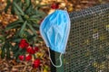 Coronavirus, concept. A blue surgical mask thrown or forgotten by the owner on the street, on the corner of a park bench Royalty Free Stock Photo