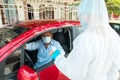 Coronavirus. A police medical technician in protective gear requests documents from a man sitting inside his car. Mobile