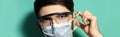 Coronavirus prevention. Panoramic portrait of young guy put on medical respiratory mask, wearing safety goggles on background.