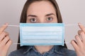 Coronavirus protection concept. Close up photo of young woman wearing blue medical mask on face isolated on grey background Royalty Free Stock Photo