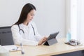 Serious professional doctor wearing white coat and stethoscope holding modern touchscreen gadget Royalty Free Stock Photo